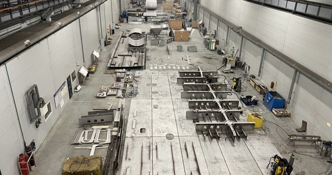 Large industrial workshop hall in Klaipeda used for stainless‑steel fabrication, welding, and assembly of heavy‑duty structural components