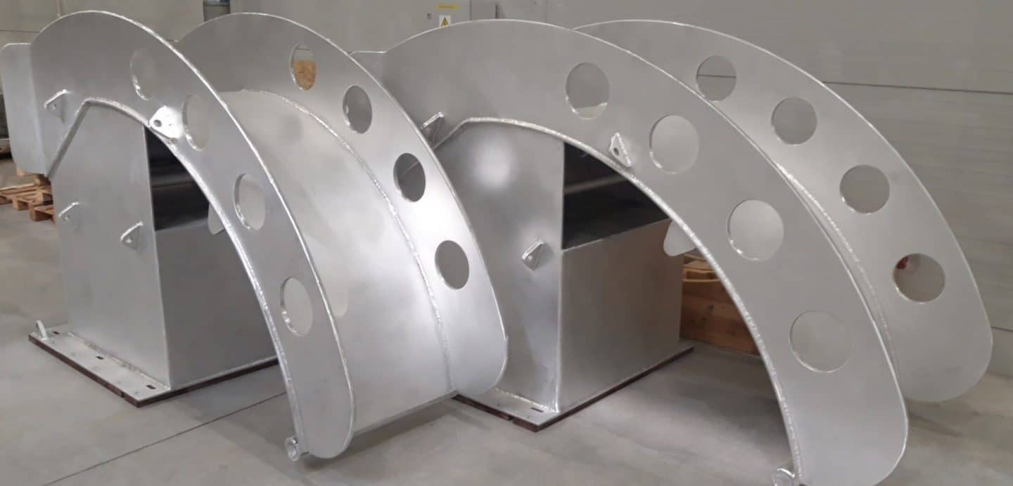 Two large welded aluminum LNG saddles designed for supporting cryogenic LNG pipelines in marine applications inside a modern workshop